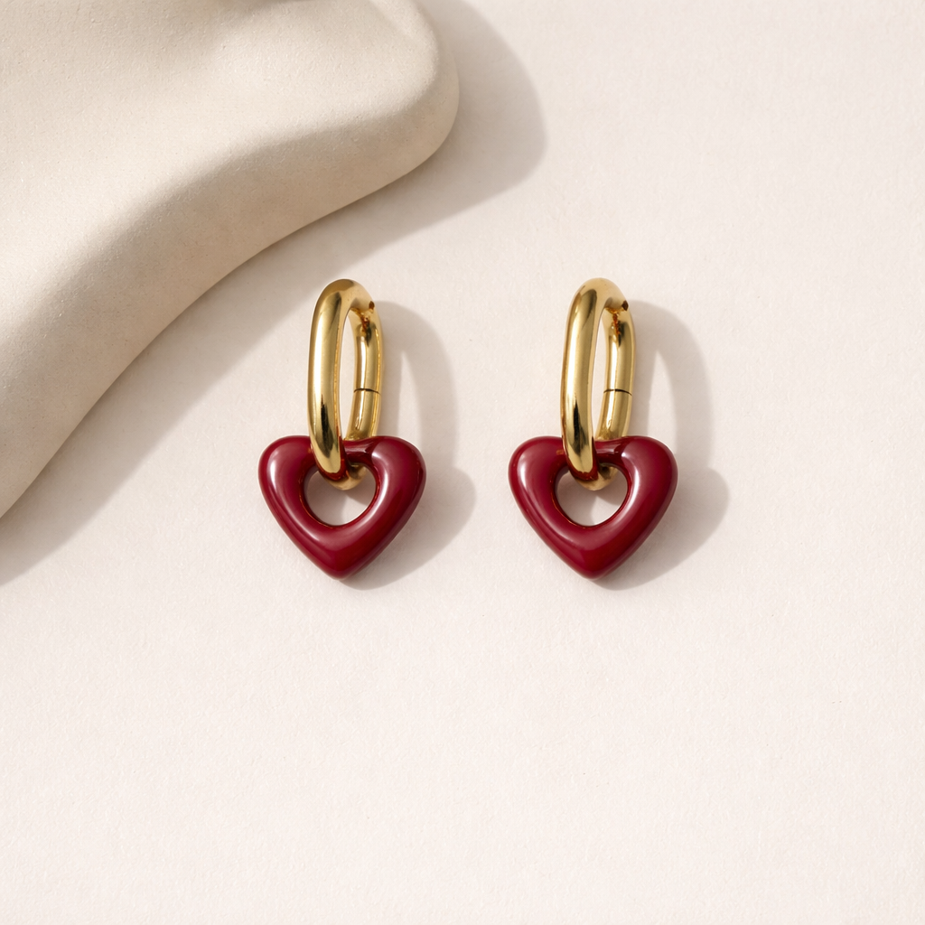 Heart-shaped earrings with gold loops on a light beige background