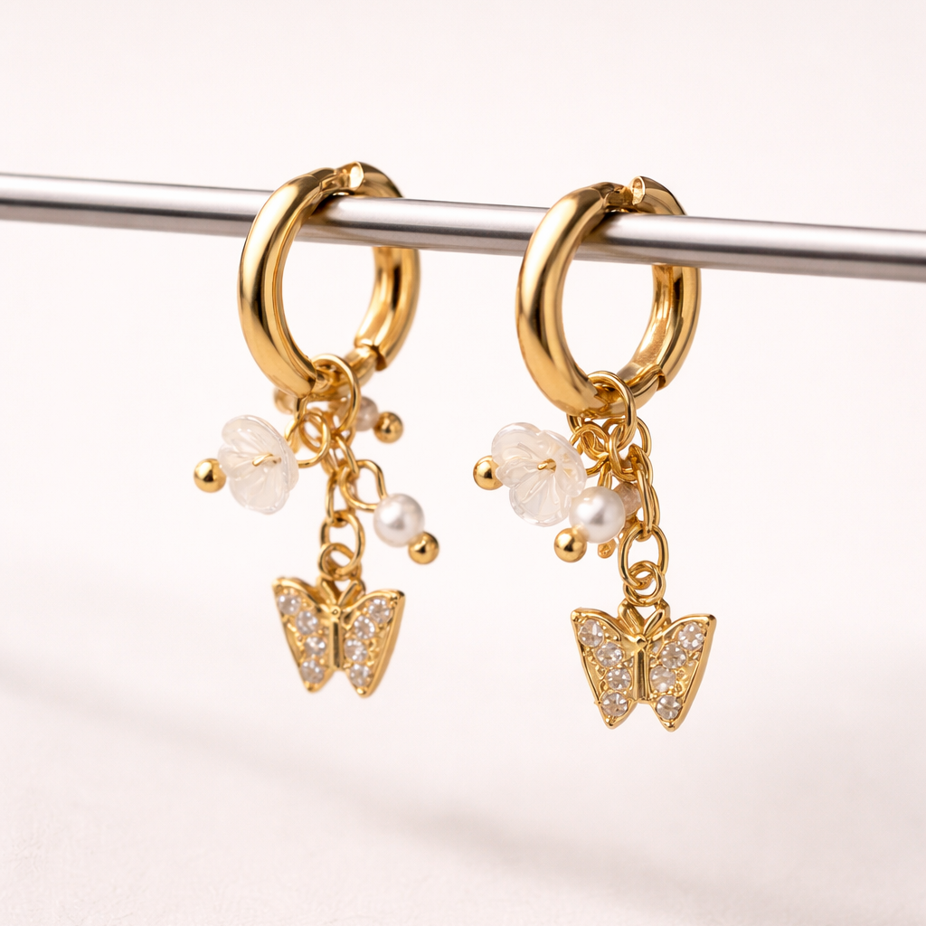 Gold hoop earrings with butterfly charms and pearl-like beads on a white background